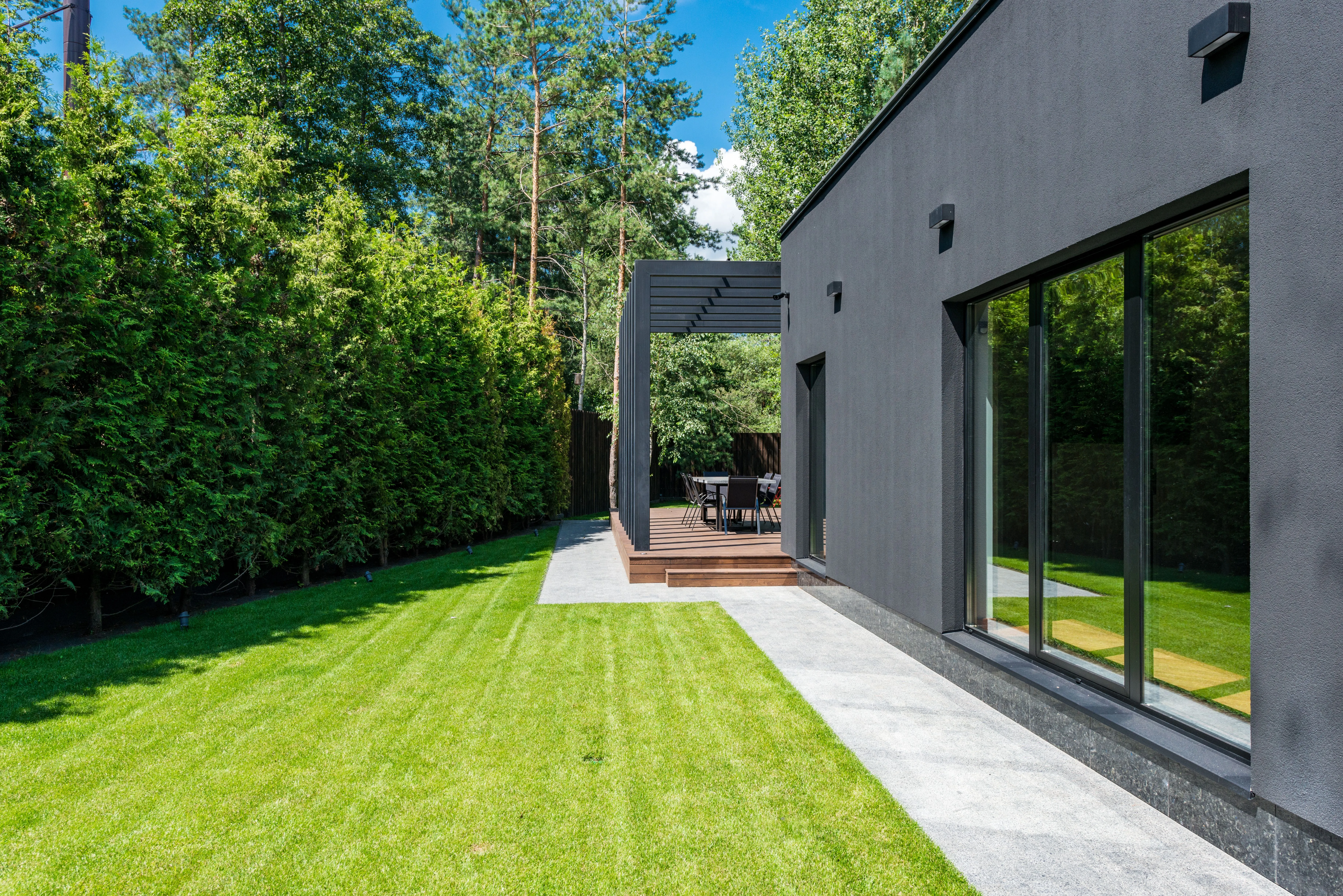 Jardín residencial con pasto, pérgola y terraza exterior